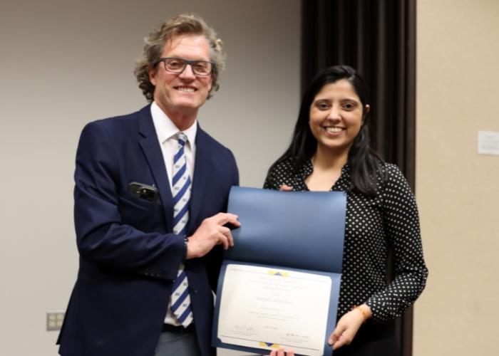 Man presenting woman with award.