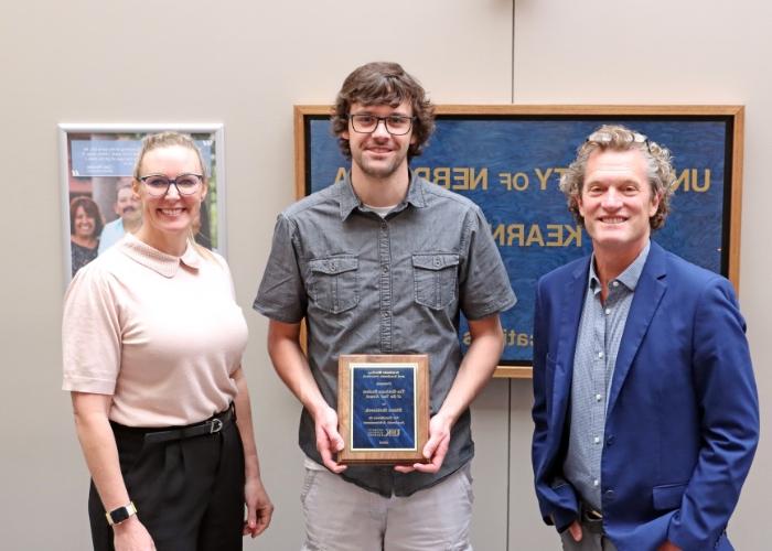 Three people posing with award.