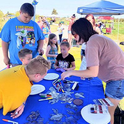 a frank house volunteer interacts with children at a community partners event